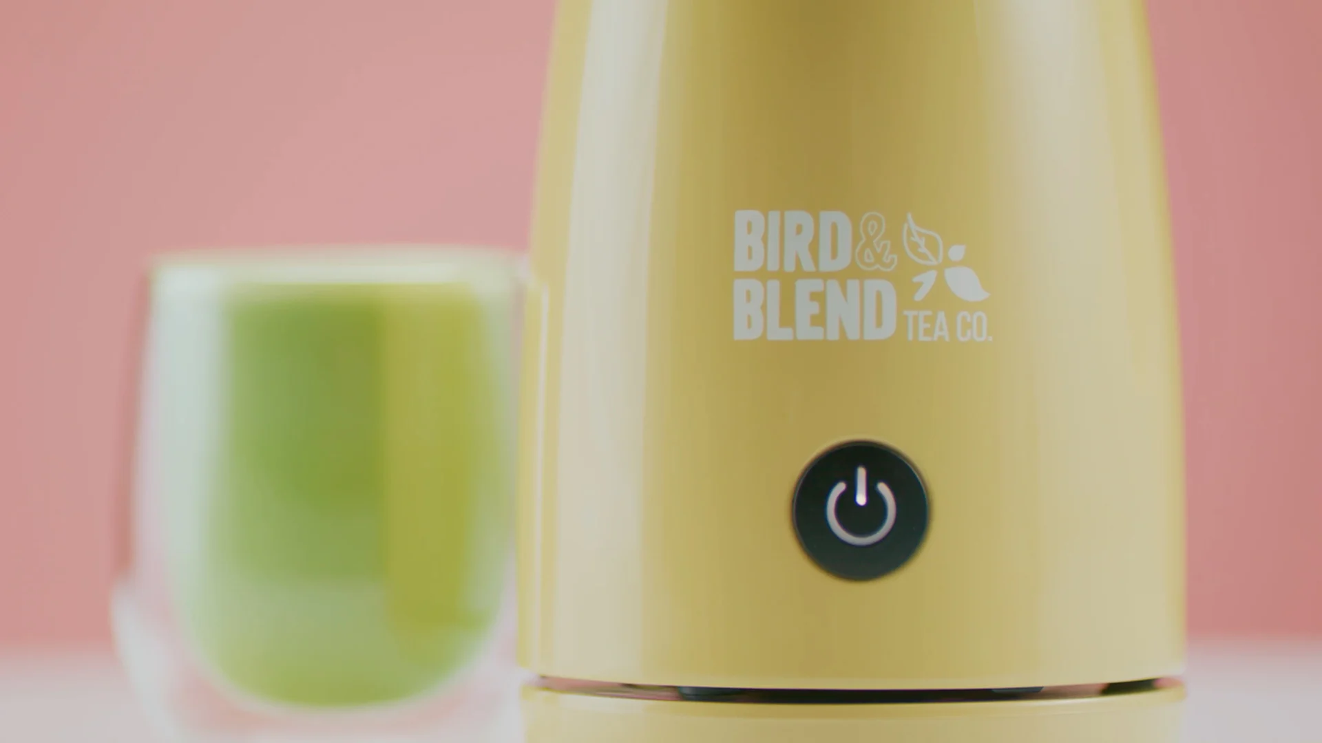 Close-up of Bird & Blend’s yellow Magic Whisk beside a glass of matcha latte.