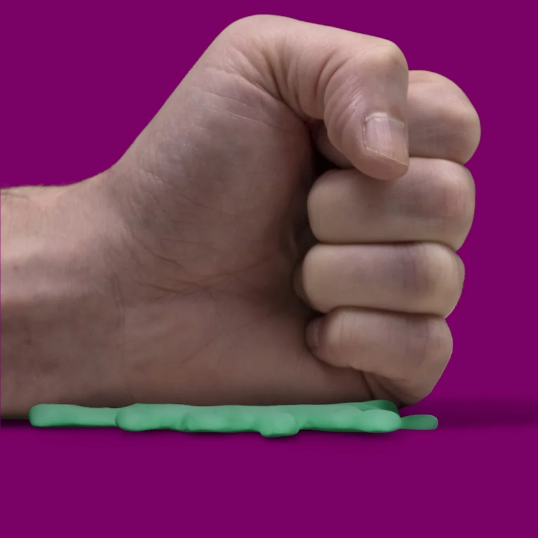 A hand pressing the green plasticine-style shape flat.